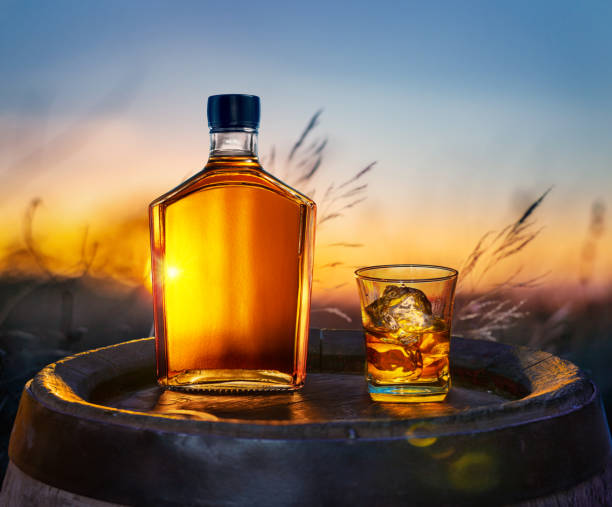 karaffe whisky und glas whisky mit eiswürfeln auf altem holzfass. wunderschöner sonnenuntergang im hintergrund. - cereal bar stock-fotos und bilder