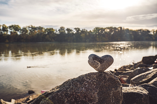 Heart shaped stone standing on a rock in the river
