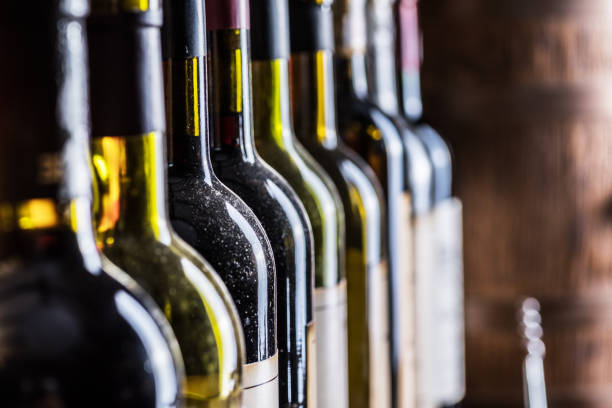 istock Wine bottles in row and oak wine keg. 1344743755