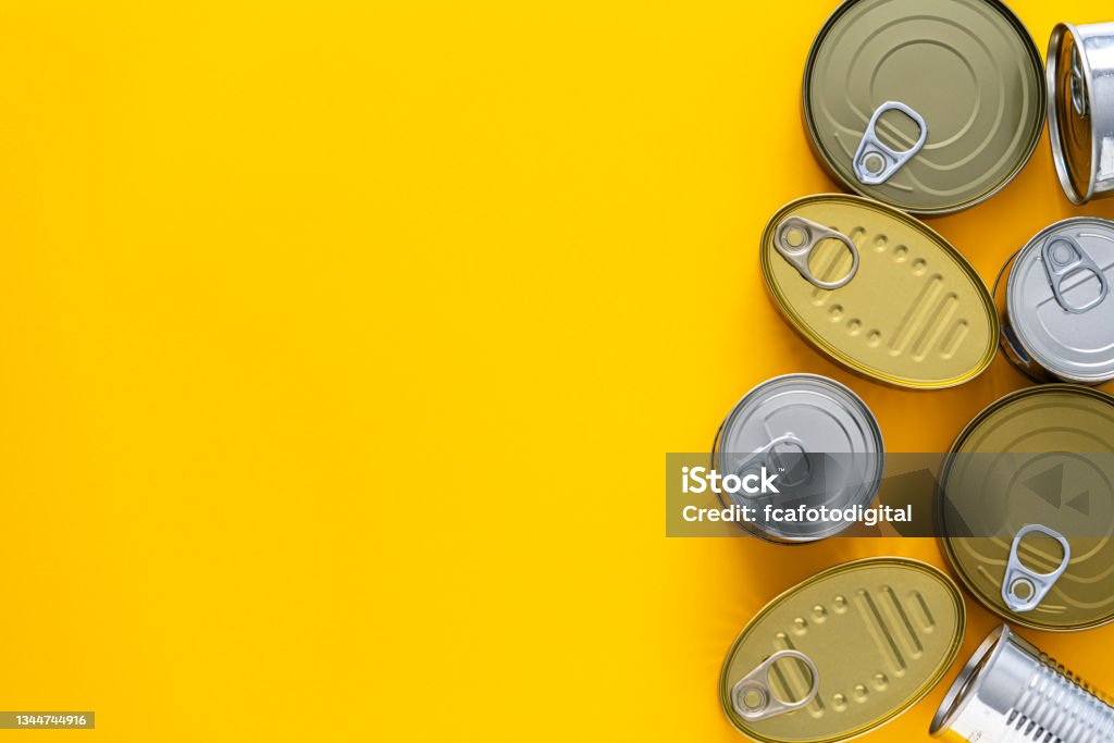 Tin cans border on yellow background Tin cans of different shapes and sizes arranged at the right border of a yellow background making a frame and leaving useful copy space for text and/or logo. At The Edge Of Stock Photo
