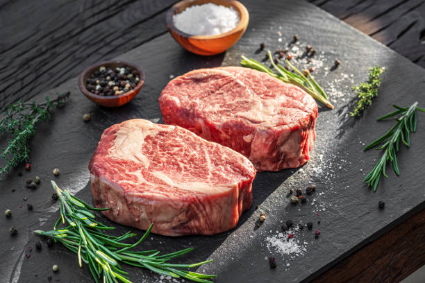 istock Raw Ribeye steaks with salt and herbs on grey board. Top view. 1344745199