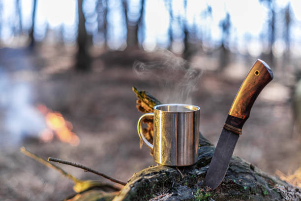 Tourist things - stainless camping cup of tea and special knife. Nature background. stock photo