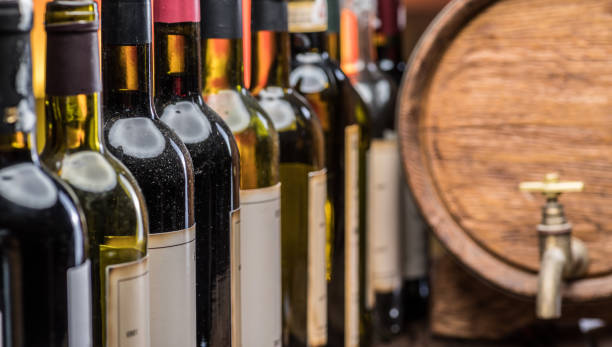 istock Wine bottles in row and oak wine keg. 1344745625