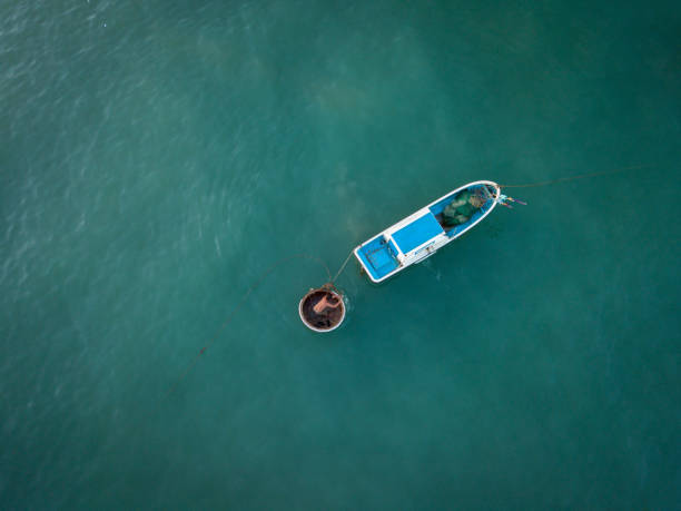 Fisherman on Nha Trang beach Drone view of a fisherman is nailing his fishing boat on Nha Trang beach- Nha Trang city, Khanh Hoa province, central Vietnam basket boat stock pictures, royalty-free photos & images