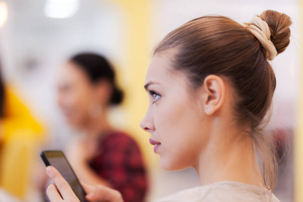 istock Beautiful girl using phone during creative meeting with coleagues. 1344748024