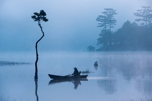 Fisherman in Tuyen Lam lake in a foggy morning, Da Lat city, Lam Dong province, central high lands Vietnam
