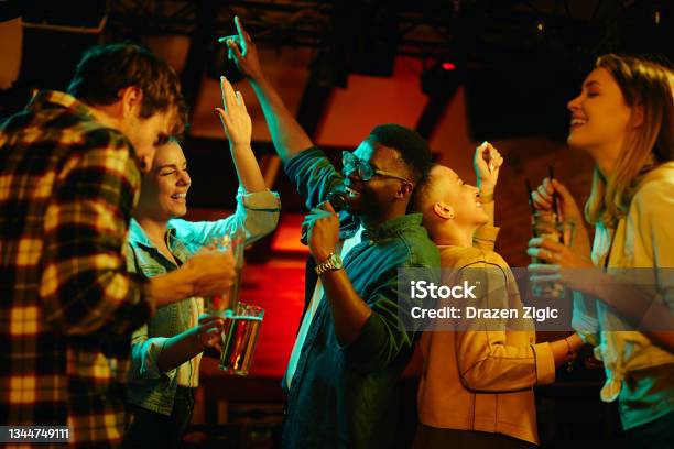 Happy Black Man Singing While Being On Karaoke Party With His Friends In A Pub Stock Photo - Download Image Now