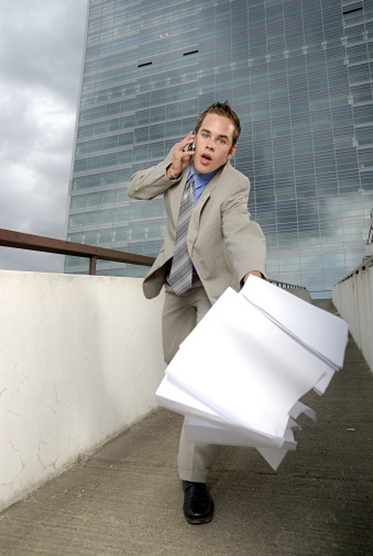 Bad day - fumbler businessman with mobile phone in front of modern business building.