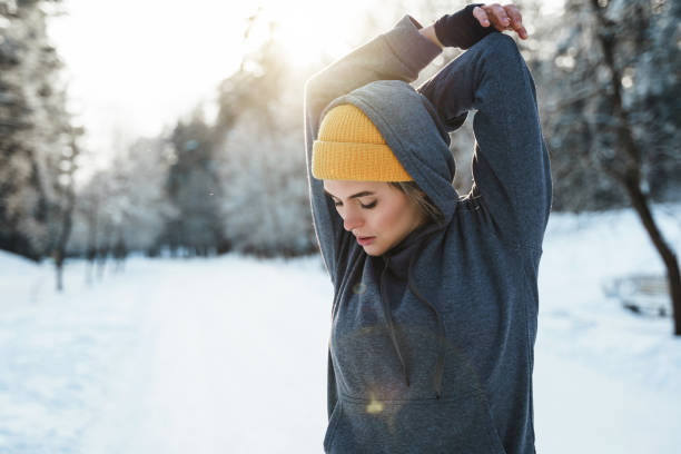 junge athletische frau beim aufwärmen vor dem wintertraining - warming up fotos stock-fotos und bilder