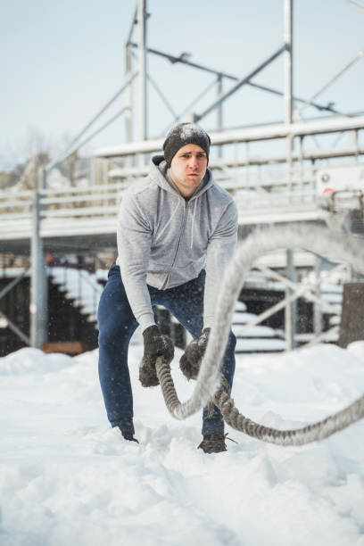 istock Young athlete working out with a battle ropes during snowy winter day. 1344752647