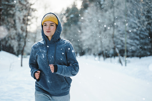 Running woman during her jogging workout during winter and snowy day