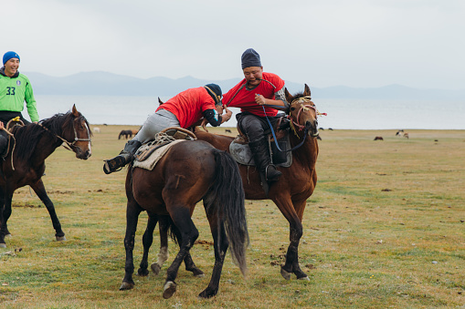 August 27th, 2020 - Group of men having fun playing an old game riding horses in the nomad village by the big lake in Kyrgyzstan