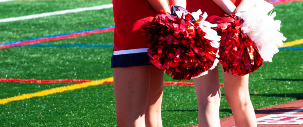 istock Two cheerleaders holding red and white pom poms behind their backs 1344755443