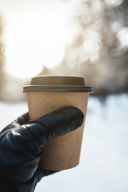 istock Hand with a paper cup of hot coffee during cold winter day 1344756863