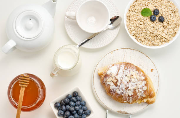 istock Raw oatmeal in white ceramic plate, blueberry, honey on white table, breakfast. top view 1344757002