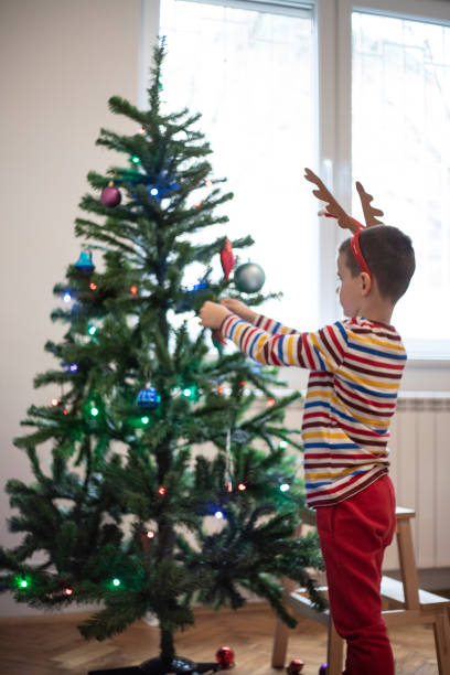 istock Boy putting ornaments on the Christmas tree 1344759210