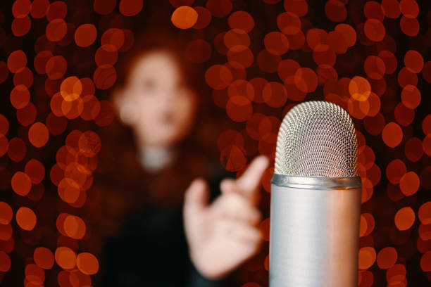 istock Woman pulls hand to microphone for sing at concert. 1344763589