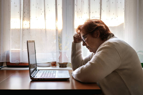 mujer mayor preocupada que navega por malas noticias en internet - frustration terrified worried glasses fotografías e imágenes de stock