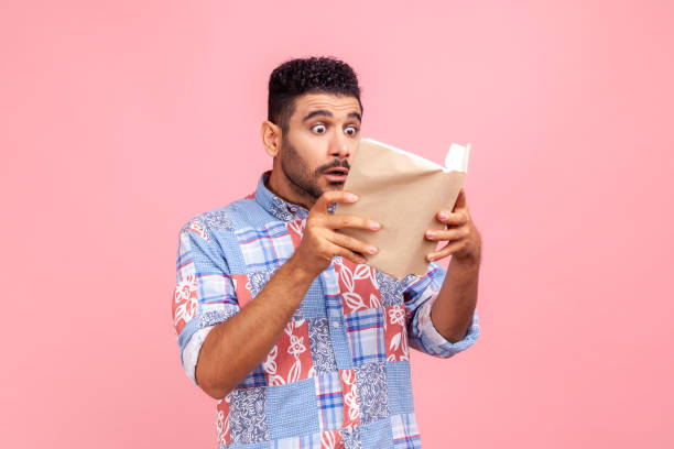 Shocking facts. Astonished smart bearded man reading book with surprised expression, amazed by story, being shocked by interesting information.