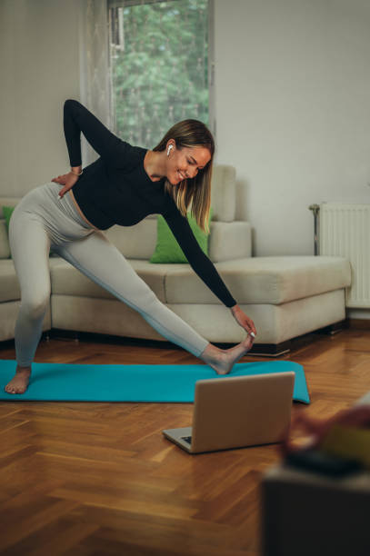 istock Woman training at home and doing fitness exercises while using laptop 1344765622