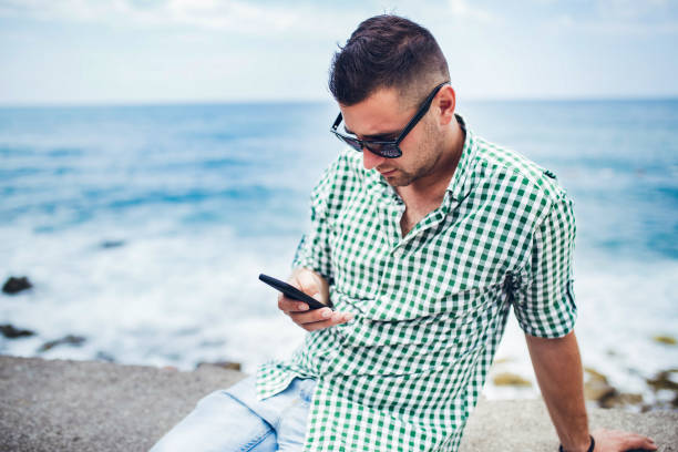 istock Young man relaxing on coast of Budva Montenegro and using mobile phone 1344766448