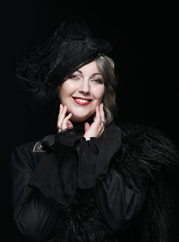 Elegant middle-aged woman in a black hat with a veil and a luxury dress. Vintage style.
