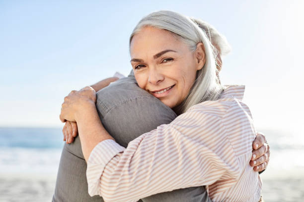 istock Mature woman embracing man at beach 1344767024