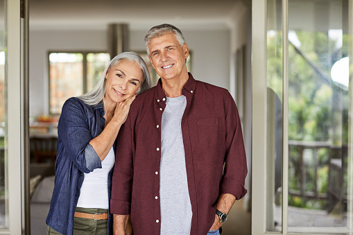 Portrait of smiling mature man and woman. Couple is spending leisure time at home during COVID-19 lockdown. They are wearing casuals.