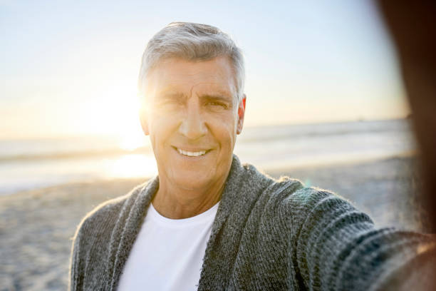 istock Close-up of smiling man taking selfie at beach 1344767891