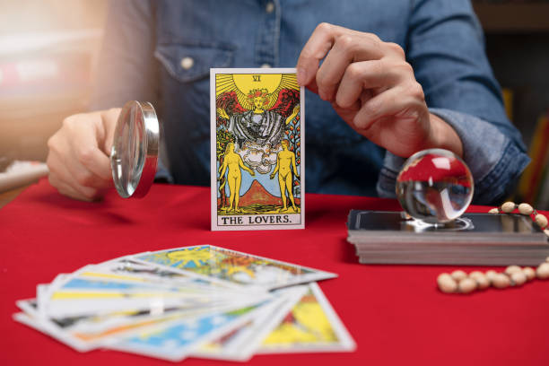 Fortuneteller holding Tarot fortune THE LOVERS card of one of the most popular occult Tarot on table. stock photo