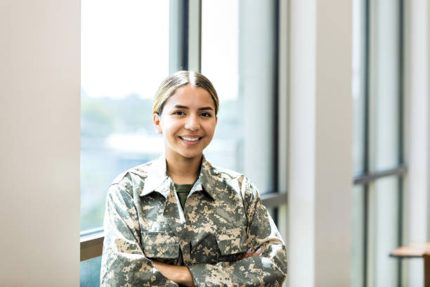 istock Female soldier smiles while standing by sunlit window 1344768770