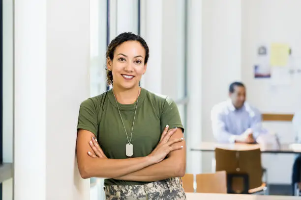 Photo of Soldier with arms crossed smiles for camera in workplace