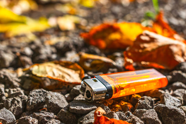 Orange lighter lies on stones among fallen leaves A bright orange lighter lies on the stones among fallen leaves, thrown onto the road by someone flint michigan stock pictures, royalty-free photos & images