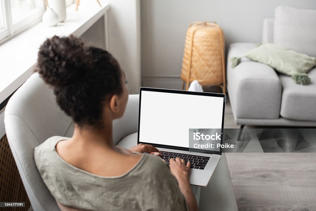 Woman using laptop computer on sofa, white blank empty screen mock-up Young woman working at home, girl studying online. Entrepreneur, business, web site add, freelance, business, studying, social distancing, distance learning, work from home, modern lifestyle, laptop mock up concept Computer Stock Photo