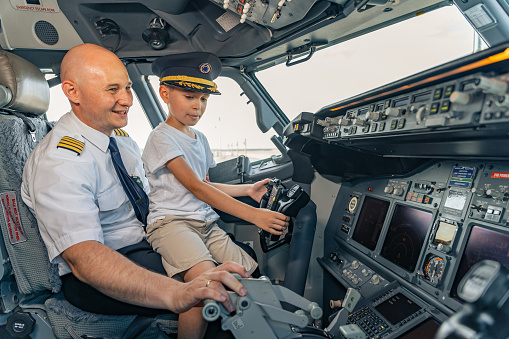Happy pilong and little boy sitting in the cockpit during the excursion. Profession concept