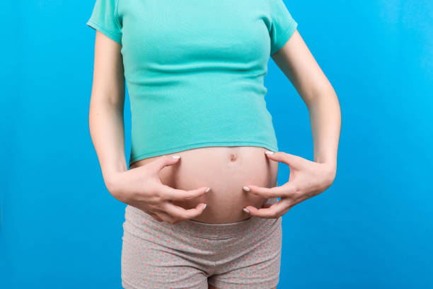 istock Pregnant woman scratching her belly on colored background 1344775814