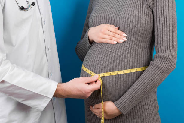 felice bella giovane donna incinta che si tocca la pancia nuda mentre un medico la sta misurando - 40 weeks foto e immagini stock
