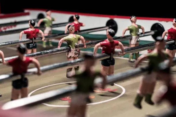 Table soccer game with red and green players. Kicker game. Dolls on a retro foosball table