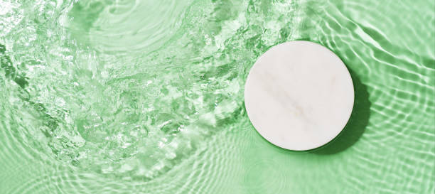 istock Transparent and clean blue water background with podium and sunlight reflection 1344777418