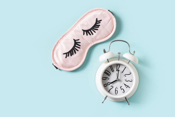 Sleep concept with mask and alarm on blue background