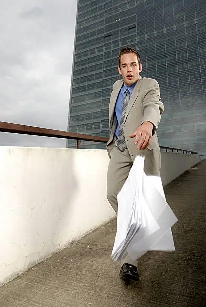 Bad day - fumbler businessman with mobile phone in front of modern business building.