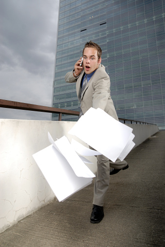 Bad day - fumbler businessman with mobile phone in front of modern business building.