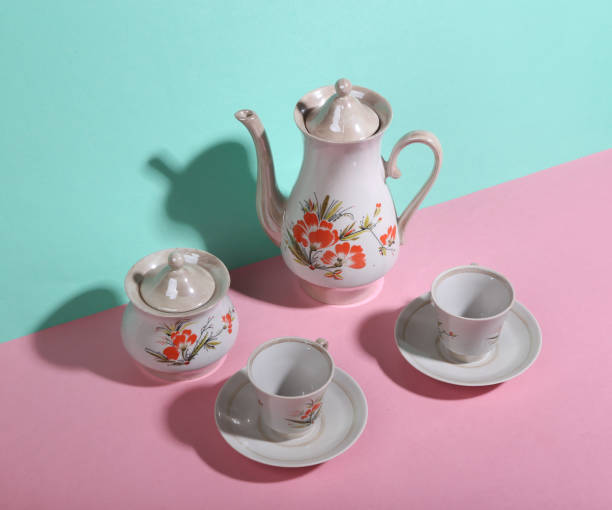 istock Retro teapot and cups on blue-pink background. Minimalism. Trendy shadow. Creative layout. 1344778589