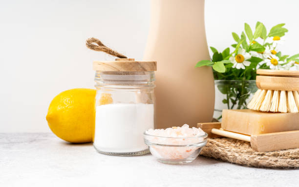 Eco friendly natural cleaners, jar with baking soda, dish brush, lemon, flowers, soap on white background. Organic ingredients for homemade cleaning with mock up bottle. Zero waste concept, copy space limpiadores naturales ecológicos, frasco con bicarbonato de sodio, cepillo para platos, limón, flores, jabón sobre fondo blanco. ingredientes orgánicos para limpiezas caseras con botella de maqueta. concepto de residuo cero, espacio de copia