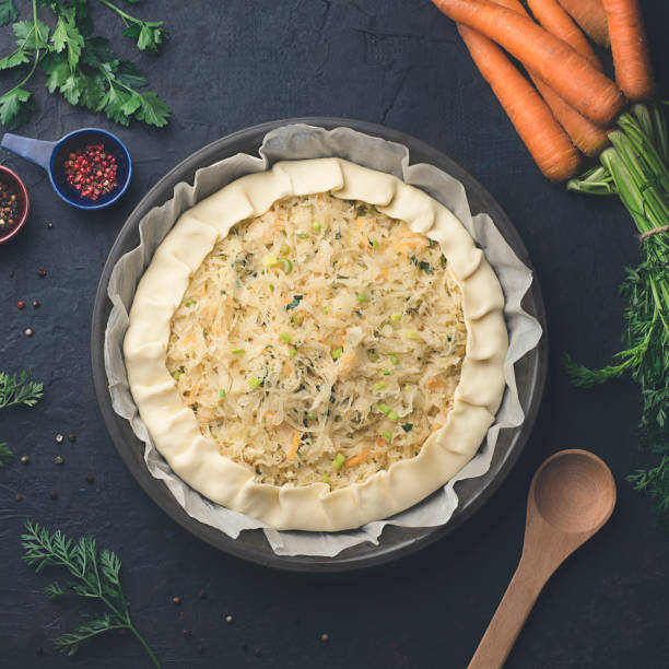 istock Homemade pie with sauerkraut or pickled cabbage, carrots and greens on dark rustic kitchen table background, preparation, top view. Vegetarian clean food. Healthy eating concept, square format 1344779458