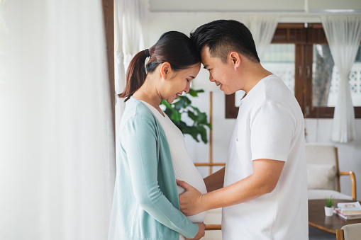 Asian couple pregnant woman with her husband feeling happy at home