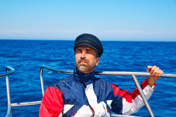 Beard sailor man sailing sea ocean in a boat with captain cap looking horizon
