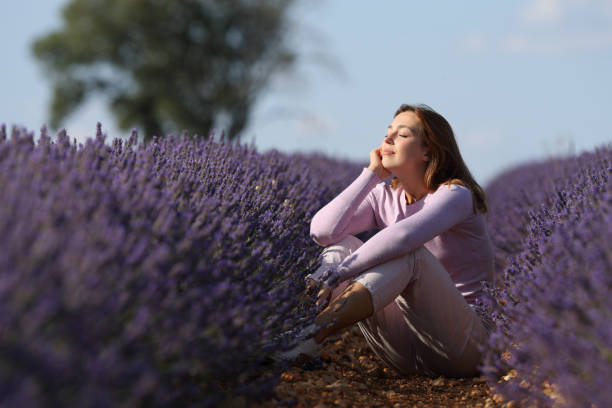 Woman relaxing sitting in a lavender field with closed eyes Woman relaxing sitting in a lavender field with closed eyes scene scented stock pictures, royalty-free photos & images