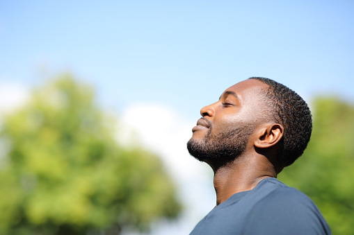 Perfil de un hombre negro respirando aire fresco en la naturaleza photo