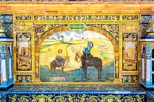 Sevilla, Spain - July 14, 2021: Historic tile bench from the Plaza de Espana in Sevilla, Spain featuring Don Quixote and Ciudad Real. The Plaza de Espana was built in 1928 for the Ibero-American Exposition of 1929 and has different cities represented all around the plaza.
